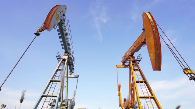 Oil Pumpjacks Working in Field Under Blue Sky