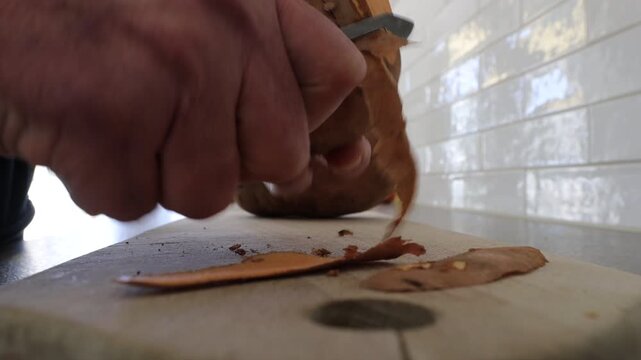 Stockholm, Sweden A cook peels a large orange sweet potato in a residential kitchen.