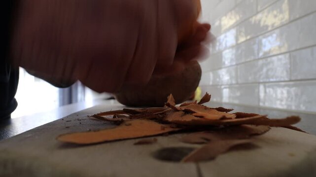 Stockholm, Sweden A cook peels a large orange sweet potato in a residential kitchen.