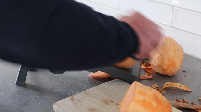 Stockholm, Sweden A cook uses a mandoline to slice sweet potatoes in a residential kitchen. 