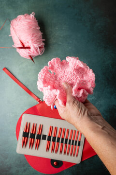 Hand holding a knitting project above a set of interchangeable, circular knitting needles on green surface.