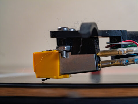 Turntable needle riding on a vinyl record with visible dust and fuzz