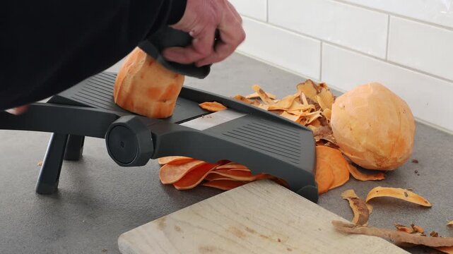 Stockholm, Sweden A cook uses a mandoline to slice sweet potatoes in a residential kitchen. 