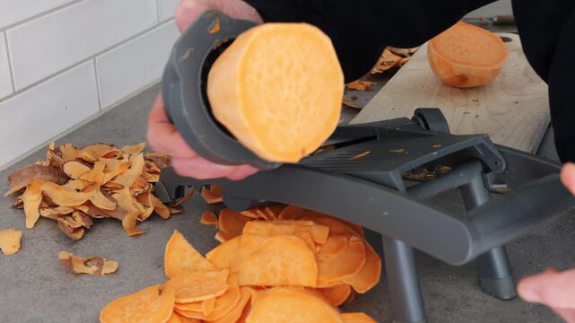 Stockholm, Sweden A cook uses a mandoline to slice sweet potatoes in a residential kitchen. 
