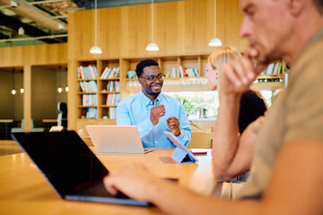 Diverse business professionals sharing ideas and working together at a table in a bright, modern coworking office space © we.bond.creations