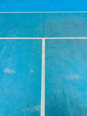 Fototapeta premium Blue tennis court with white lines showing wear and tear from use with marks and dirt visible on surface