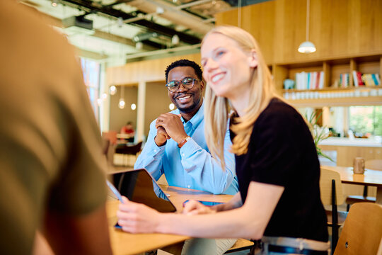 Young diverse business colleagues meeting and discussing ideas in a comfortable, modern co-working space, smiling and happy