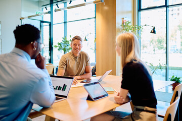 Diverse business professionals discussing data and strategy during a meeting, smiling and...