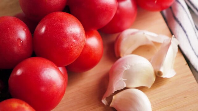 Close up of fresh red tomatoes and garlic on wooden surface, healthy ingredients for cooking concept. High quality 4k footage
