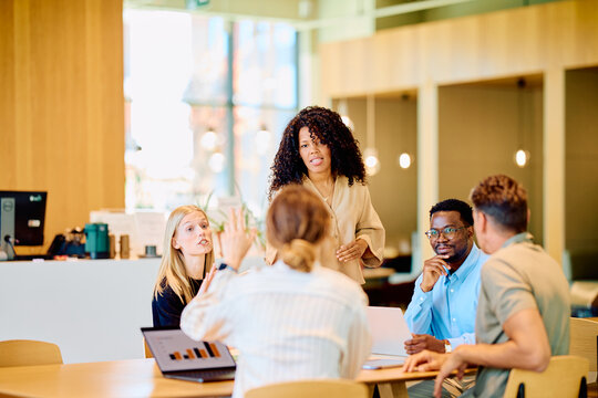 Diverse business professionals conducting an informal meeting, discussing ideas and planning strategy in a modern office environment