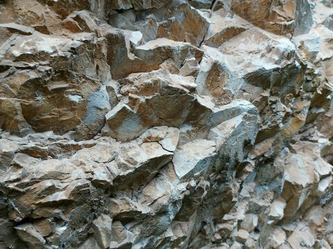 Layered rock face texture with sharp diagonal fractures and detailed stone surface