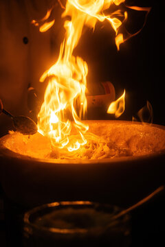 Pasta preparation with chef using torch at restaurant during evening service
