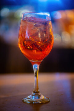 An aperol spritz drink on a glass at a lively bar during the evening with defocused background