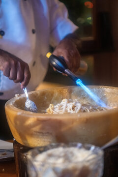 Pasta preparation with chef using torch at restaurant during evening service
