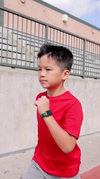10 year old boy runs on his school's track.
