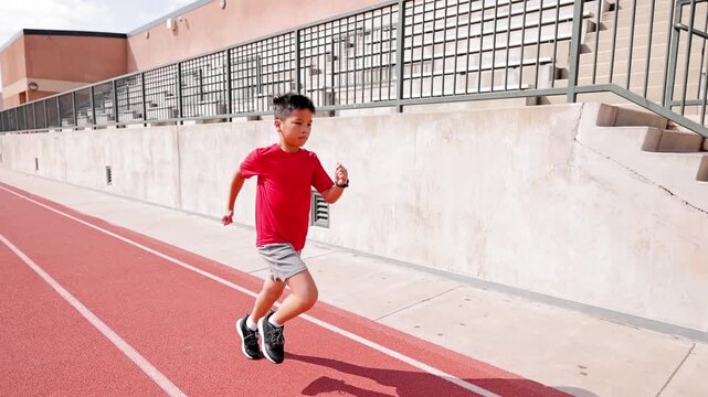 10 year old boy runs on his school's track.