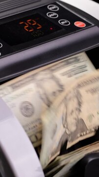 Money counting machine. Currency counting machine counting US money. Slow Motion, vertical video.