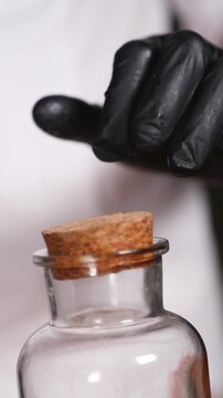 Chef sellando un frasco de jarabe de durazno con tapa de corcho. Un chef profesional cierra un frasco de jarabe de durazno casero con corcho. Conservaci&oacute;n de alimentos, proceso artesanal.