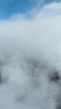 Aerial shot of the clouds and the rugged terrain of the Wasatch Mountains near Salt Lake City, Utah. Vertical Video.