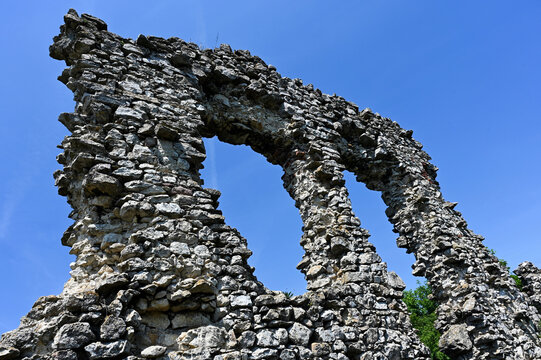 stone arches of ancient castle ruins in low angle perspective view. medieval castle and fortress at Csovar in Northern Hungary near Vac. blue sky background. rough stone texture. tilted view.