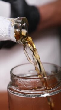Chef vertiendo licor en un frasco vac&iacute;o (primer plano). Chef profesional llenando un frasco vac&iacute;o con licor. Conserva artesanal, primer paso de una receta gourmet.