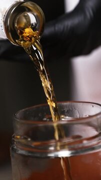 Chef vertiendo licor en un frasco vac&iacute;o (primer plano). Chef profesional llenando un frasco vac&iacute;o con licor. Conserva artesanal, primer paso de una receta gourmet.