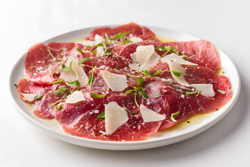 Obraz premium Classic Italian Beef Carpaccio on a Full Plate with Fresh Herbs and Parmesan
