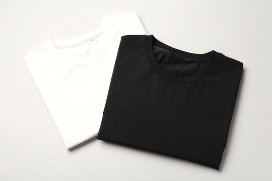 Blank folded t-shirts on light grey background, top view. Mockup for design