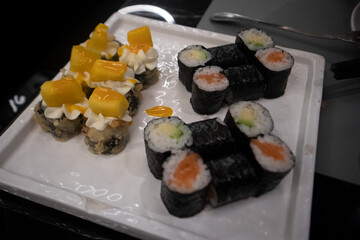 Assortimento di sushi maki giapponesi con salmone e avocado avvolti in alga nori serviti su un piatto bianco © Ilarialapreziosa