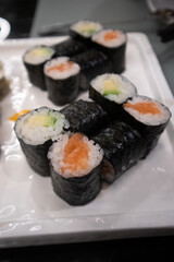 Assortimento di sushi maki giapponesi con salmone e avocado avvolti in alga nori serviti su un piatto bianco © Ilarialapreziosa