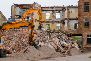 Fototapeta premium Heavy excavators demolishing old brick building with rubble and timber debris at urban site