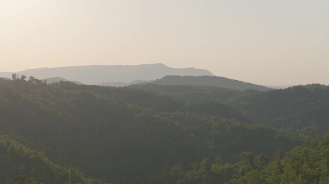 Dark silhouette of large mountains, hills, and terrain of Smoky Mountains in distance from Gatlinburg and Pigeon Forge in moody lighting with trees, forest, wildlife, mountain range, and drone aerial