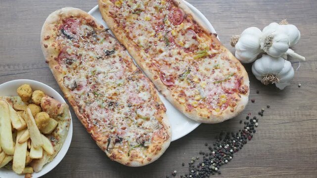 Close-up of sliced rectangular mixed pizza with rich toppings on wooden board