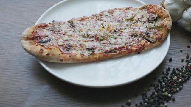 Close-up of sliced rectangular mixed pizza with rich toppings on wooden board