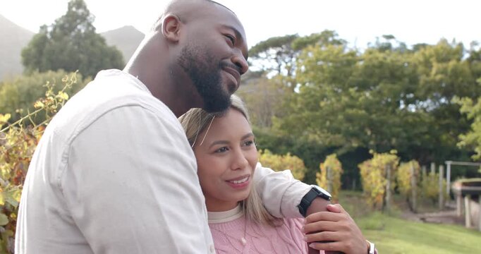 Diverse couple, after woman pointing, embracing in park, showing watch and necklace, admiring view