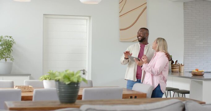 Couple standing in open kitchen, man pointing at tablet while both reviewing screen, copy space