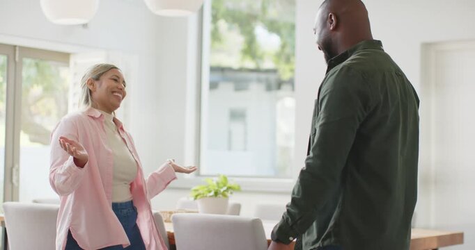 Couple wearing pink and green exchanging open palms, showing warmth at dining table