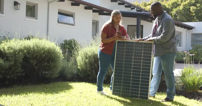 African American owner and installer placing solar panel at front yard using phone planning install