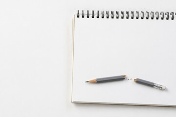 Naklejka premium Broken pencil lying on blank spiral notebook. Space for text.