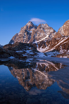 Monviso or Mount Viso mountain range reflected in the crystalline waters of Lake Superiore at sunrise on a spring day. Monviso natural Park, Po valley, Cottian Alps, Piedmont, italy.