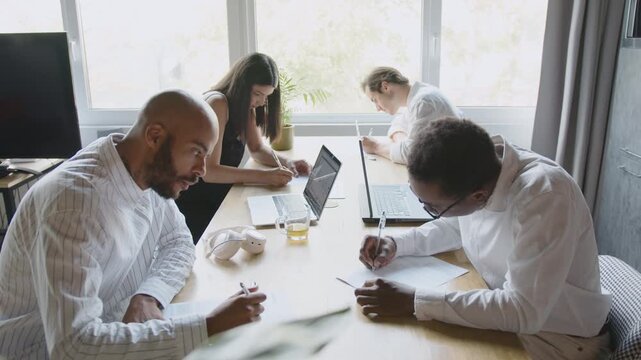 Diverse team collaborates on contract paperwork in a bright office setting