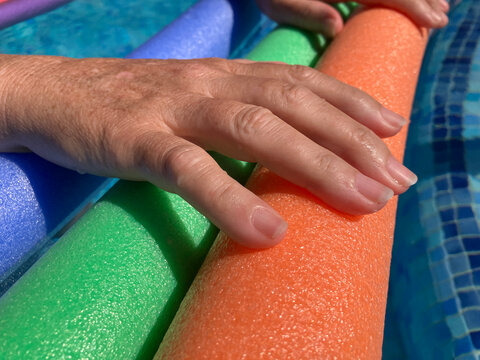 Woman's hands on  pool noodles, close up