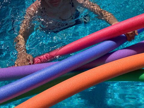 Woman in swimming pool with colourful swim floats, summer holiday vibes