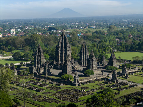 Aerial view of the Prambanan Temple complex with towering stone structures and lush green surroundings with a volcano in the distance Kecamatan Prambanan, Daerah Istimewa Yogya, Indonesia.