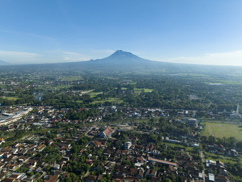 Aerial view of Prambanan Temple and Mount Merapi overlooking the urban landscape and lush greenery in Kecamatan Prambanan, Daerah Istimewa Yogya, Indonesia.