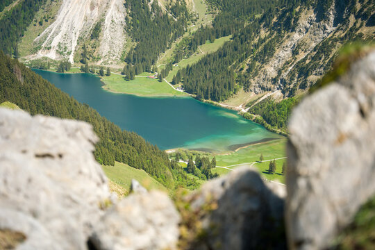 Turquoise Mountain Lake Surrounded by Pine Forests and Alpine Meadows Seen from Rocky Overlook