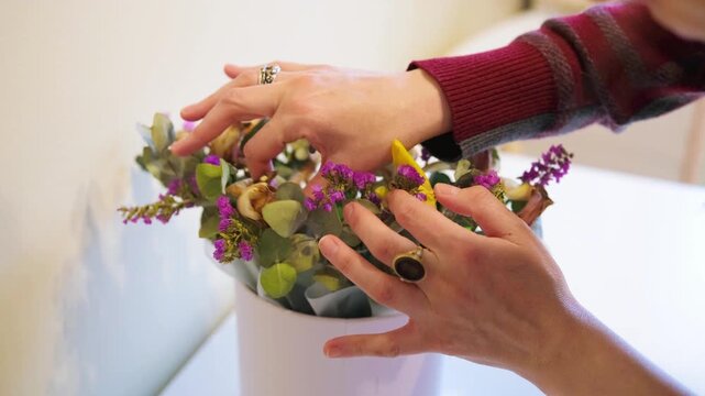 Female Hands Inspecting Mixed Floral Arrangement With Eucalyptus