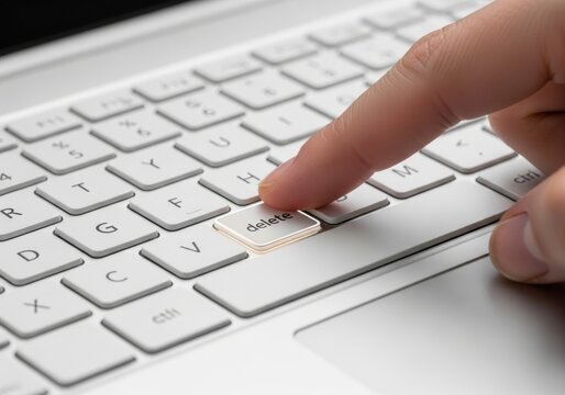 Finger pressing delete key on a computer keyboard isolated on white background
