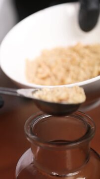 Chef a&ntilde;adiendo avellanas trituradas a un tarro de ron: una creaci&oacute;n vanguardista. Un chef profesional combina avellanas trituradas con ron a&ntilde;ejo. Elaboraci&oacute;n culinaria moderna y vanguardista.