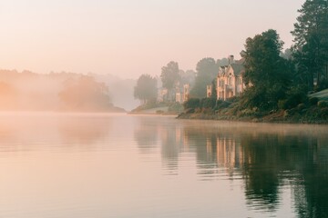 Fototapeta premium Luxury homes on misty lakefront at sunrise, soft golden hour glow, tranquil atmosphere